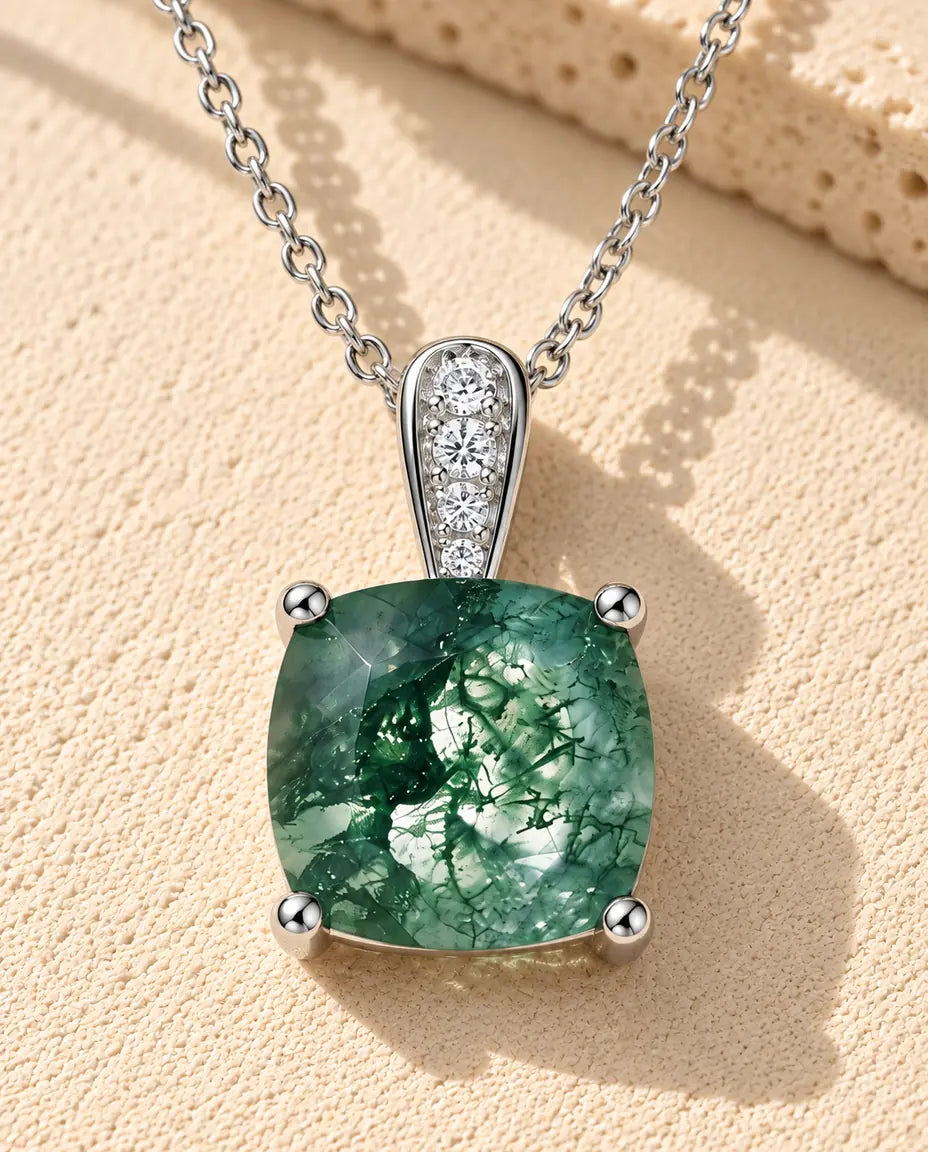 Cushion Moss Agate Pendant Necklace in 925 Sterling Silver - lying on a cream textured surface beside a travertine block
