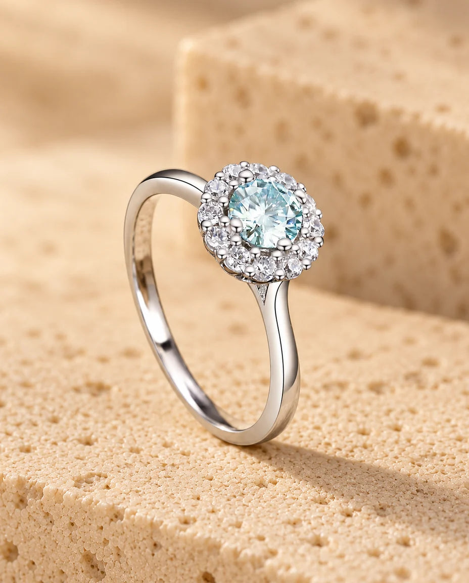 Green Teal Moissanite Halo Ring - displayed on a travertine block