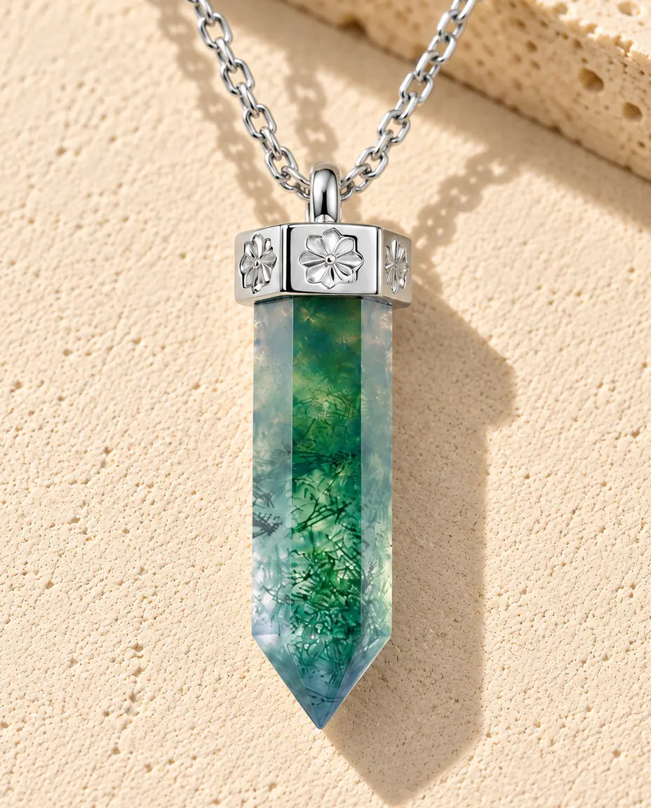 Moss Agate Point Necklace in 925 Sterling Silver - lying on a cream textured surface beside a travertine block