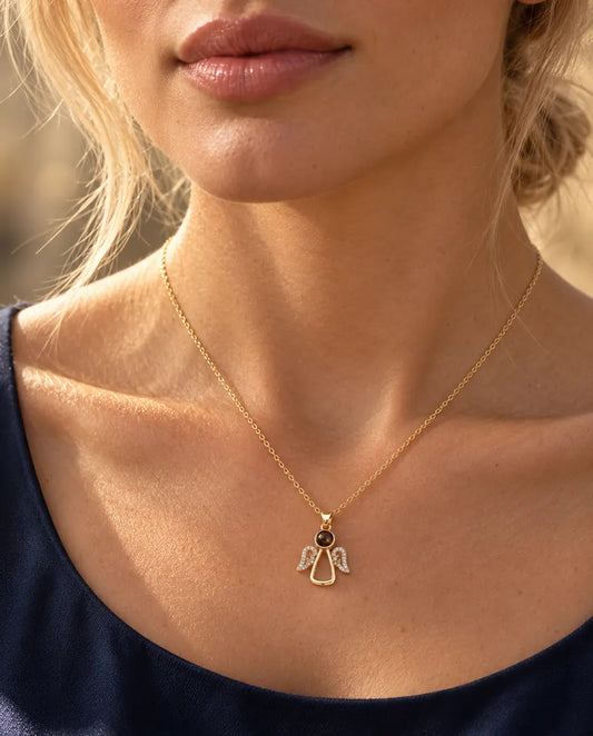 Woman in a navy top wearing the gold tone angel photo projection necklace
