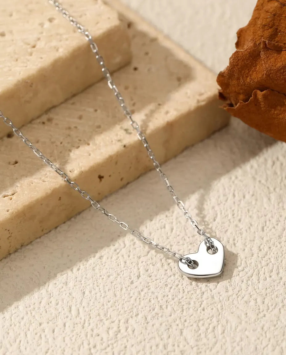 Heart Necklace in 925 Sterling Silver - pendant resting on a cream surface beside a travertine slab