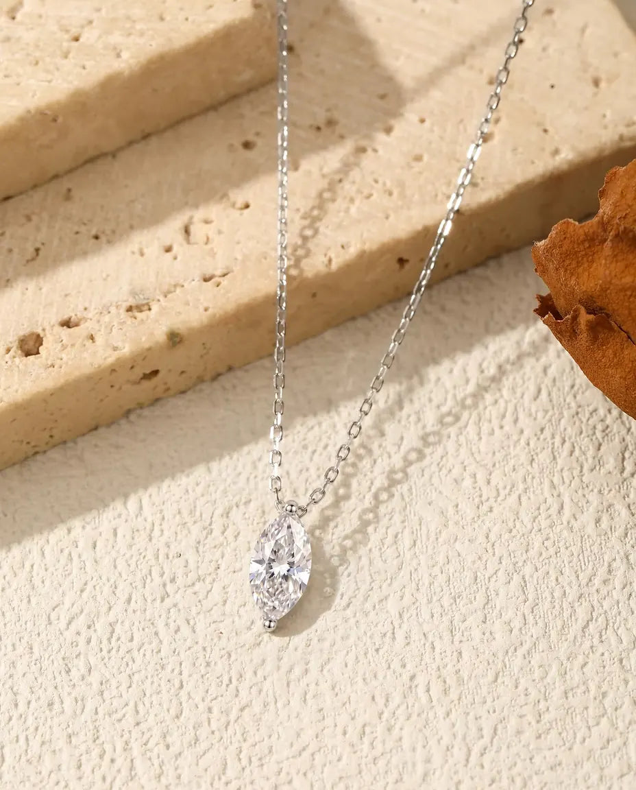 1 ct Marquise Moissanite Necklace in 925 Sterling Silver - pendant hanging over the edge of a travertine slab