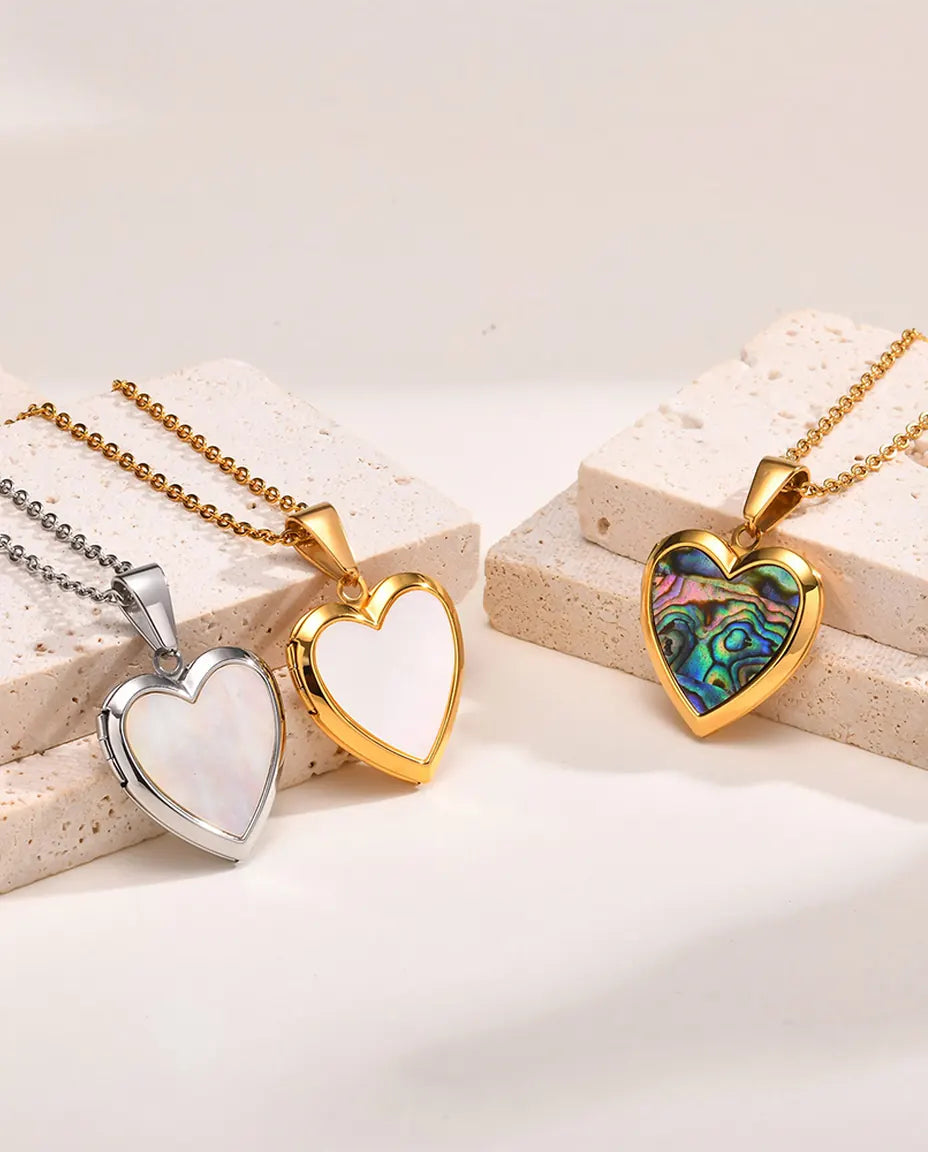 Three heart shell lockets side by side — silver mother of pearl, gold mother of pearl and gold abalone