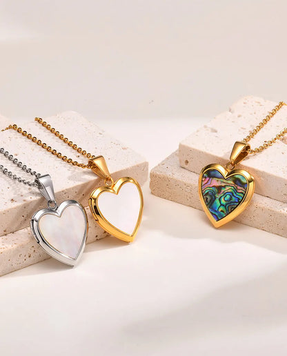 Three heart shell lockets side by side — silver mother of pearl, gold mother of pearl and gold abalone