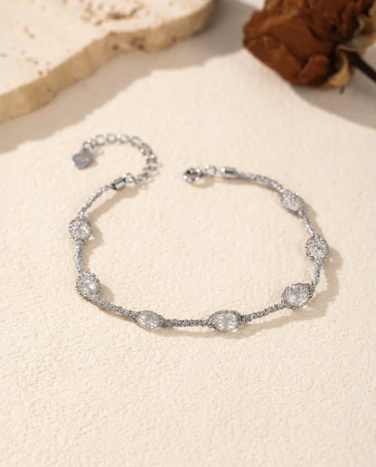 Caged Zircon Bracelet in 925 Sterling Silver - white zircon version laid flat on a cream surface