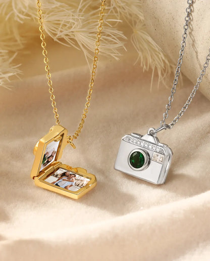 Camera locket open showing two photos inside, in gold and silver