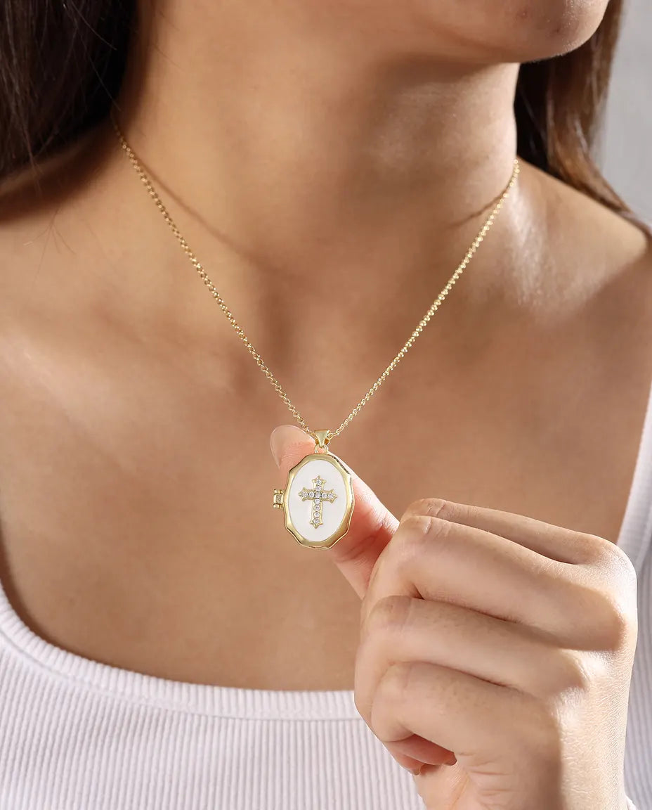 Woman wearing white enamel cross photo locket necklace in gold tone