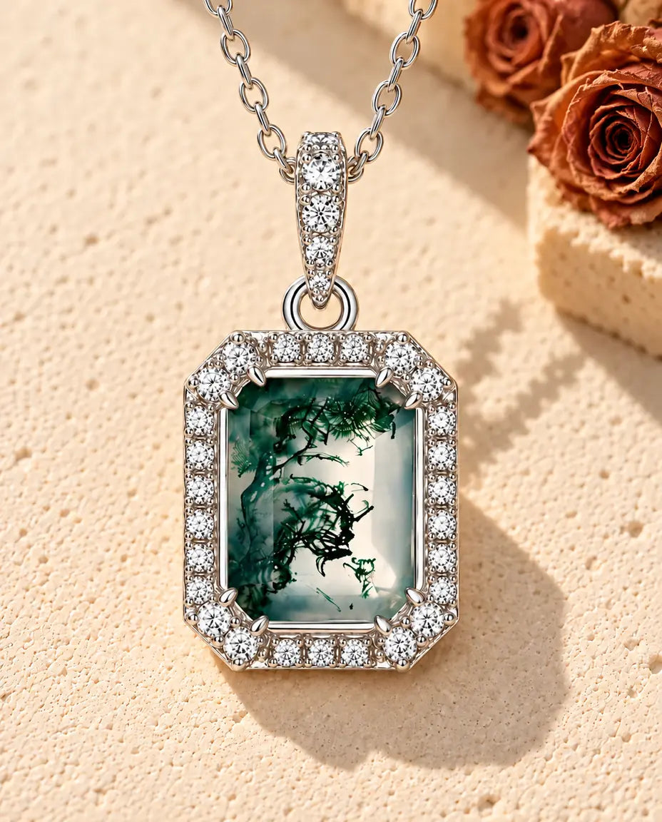 Emerald Cut Moss Agate Halo Necklace in 925 Sterling Silver - lying on a cream textured surface beside a travertine block