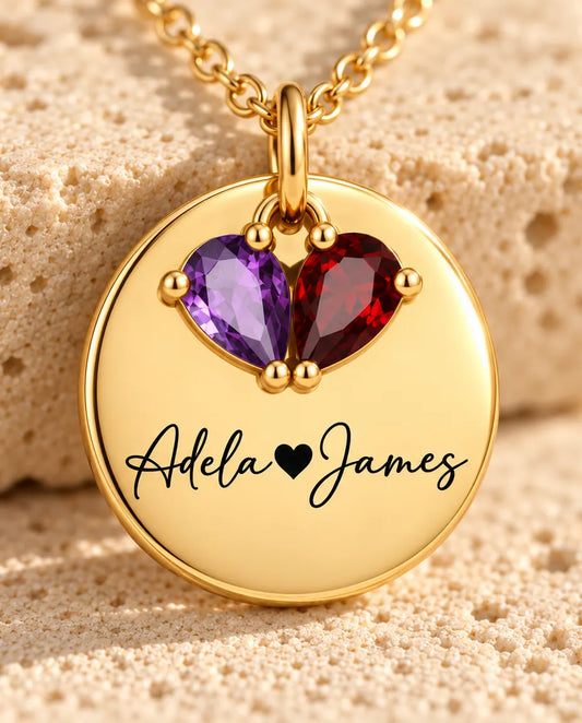 Close-up of the gold disc engraved with two names in script and two pear birthstones