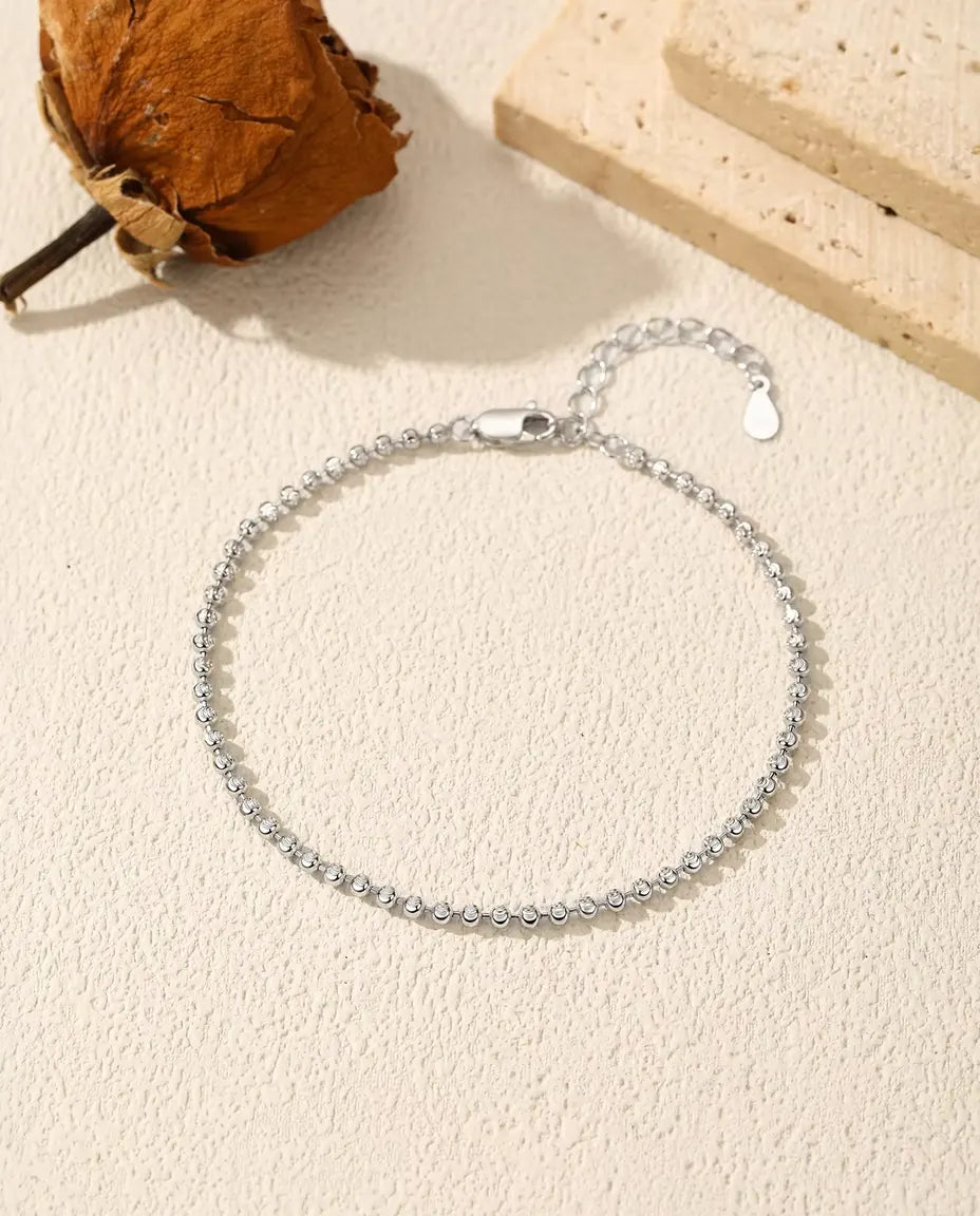 Faceted Bead Bracelet in 925 Sterling Silver - laid flat on a cream textured surface with the clasp and extender