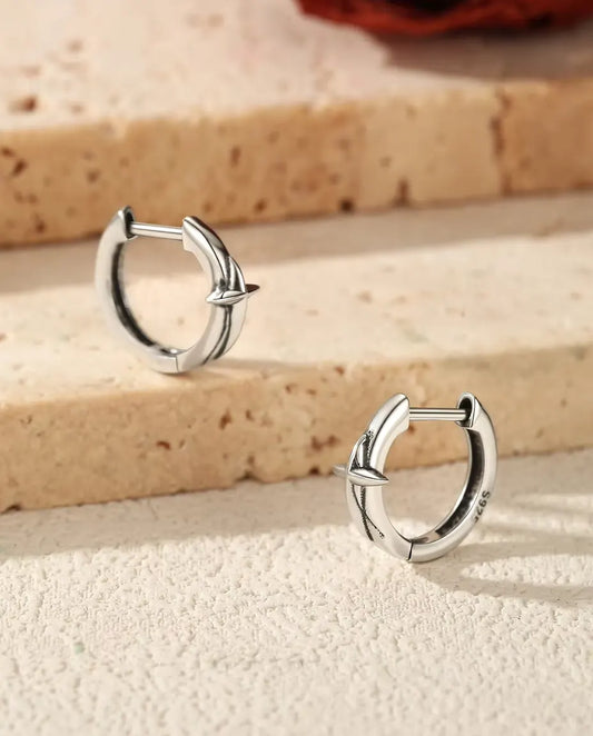 Star Huggie Hoop Earrings in 925 Sterling Silver - the pair resting on travertine steps