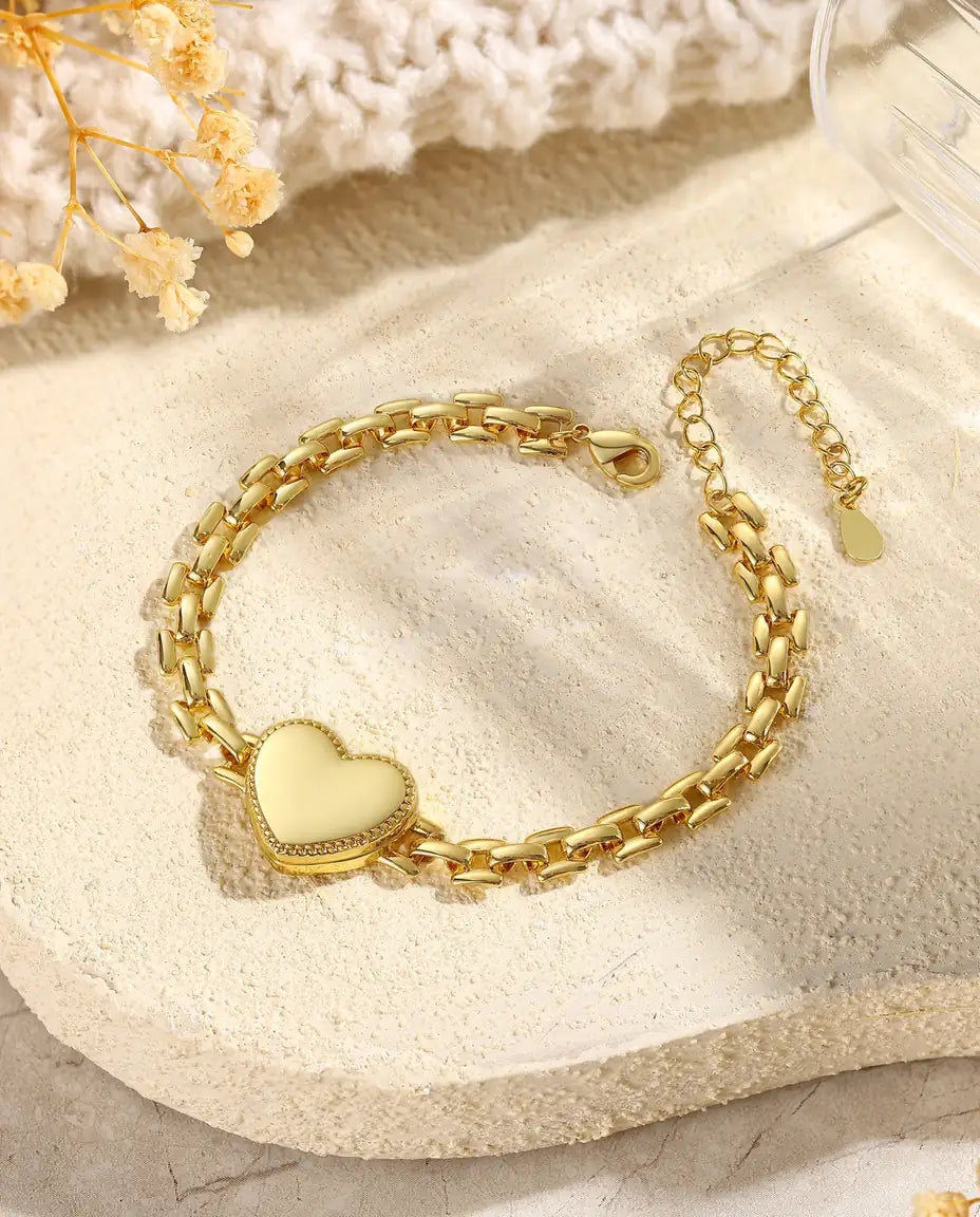 Gold heart locket bracelet closed on stone flatlay with dried flowers