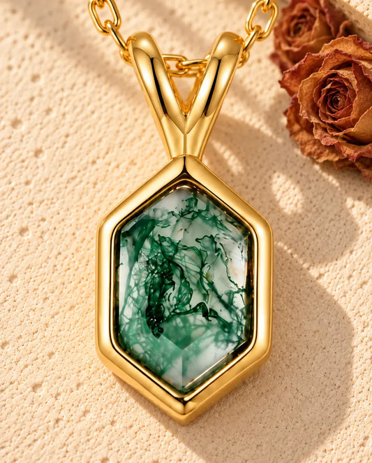 Hexagon Moss Agate Necklace in 10K Gold Plated 925 Sterling Silver - lying on a cream textured surface beside a travertine block