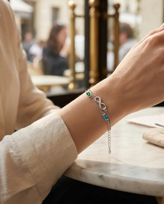 Woman wearing the infinity birthstone bracelet with two birthstones at a cafe table