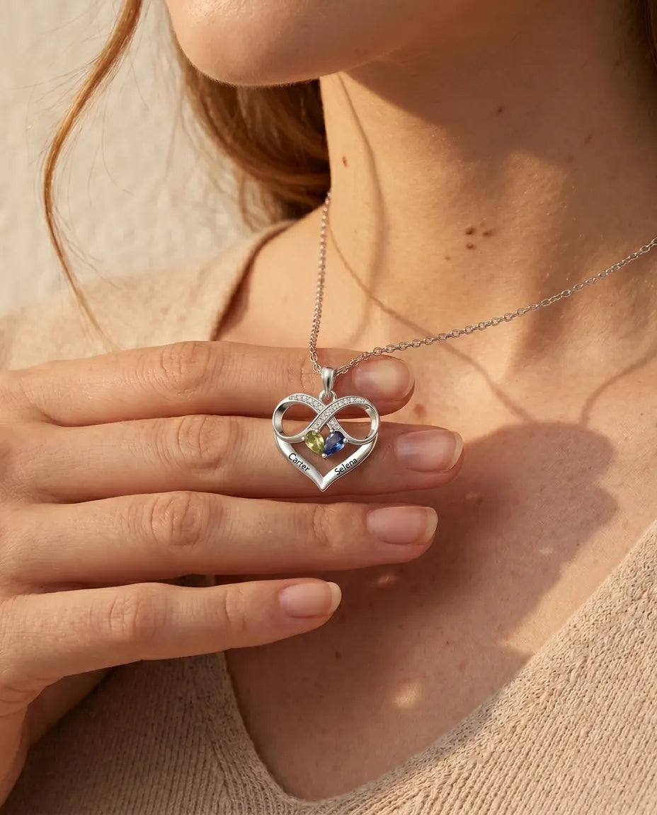 Infinity heart birthstone pendant held between the fingers