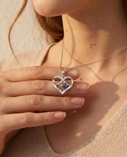 Infinity heart birthstone pendant held between the fingers