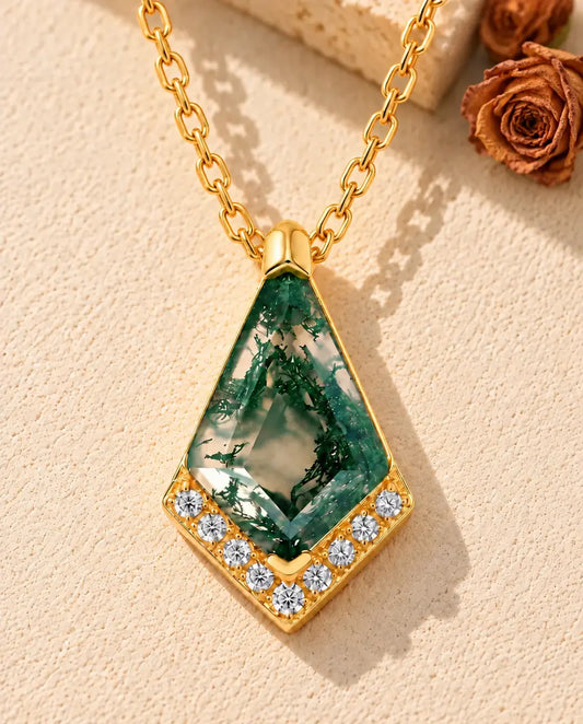 Kite Moss Agate Necklace in 10K Gold Plated 925 Sterling Silver - lying on a cream textured surface beside a travertine block