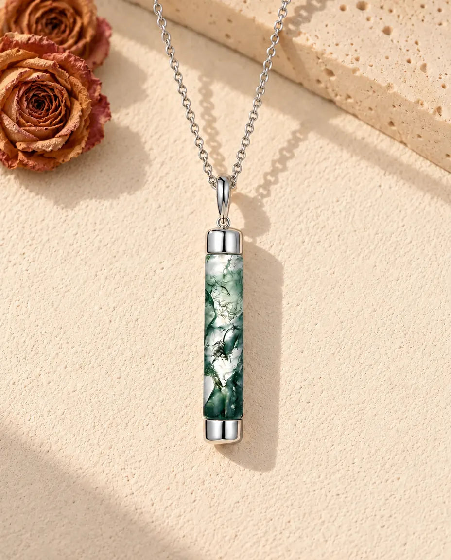 Moss Agate Bar Necklace in 925 Sterling Silver - lying on a cream textured surface beside a travertine block