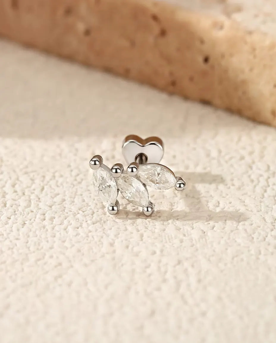 Marquise Moissanite Leaf Stud Earrings in 925 Sterling Silver - lying on a cream textured surface beside a travertine slab