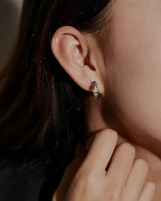 Moissanite Cross Hoop Earrings in 925 Sterling Silver - worn on a model’s ear, hand near her face