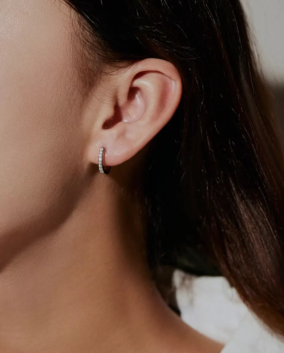 Moissanite Huggie Hoop Earrings in 925 Sterling Silver - worn on a model’s ear, side profile
