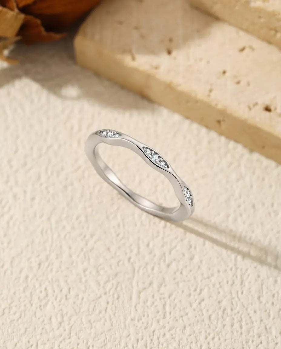 Moissanite Wave Ring in 925 Sterling Silver - standing upright on a cream textured surface