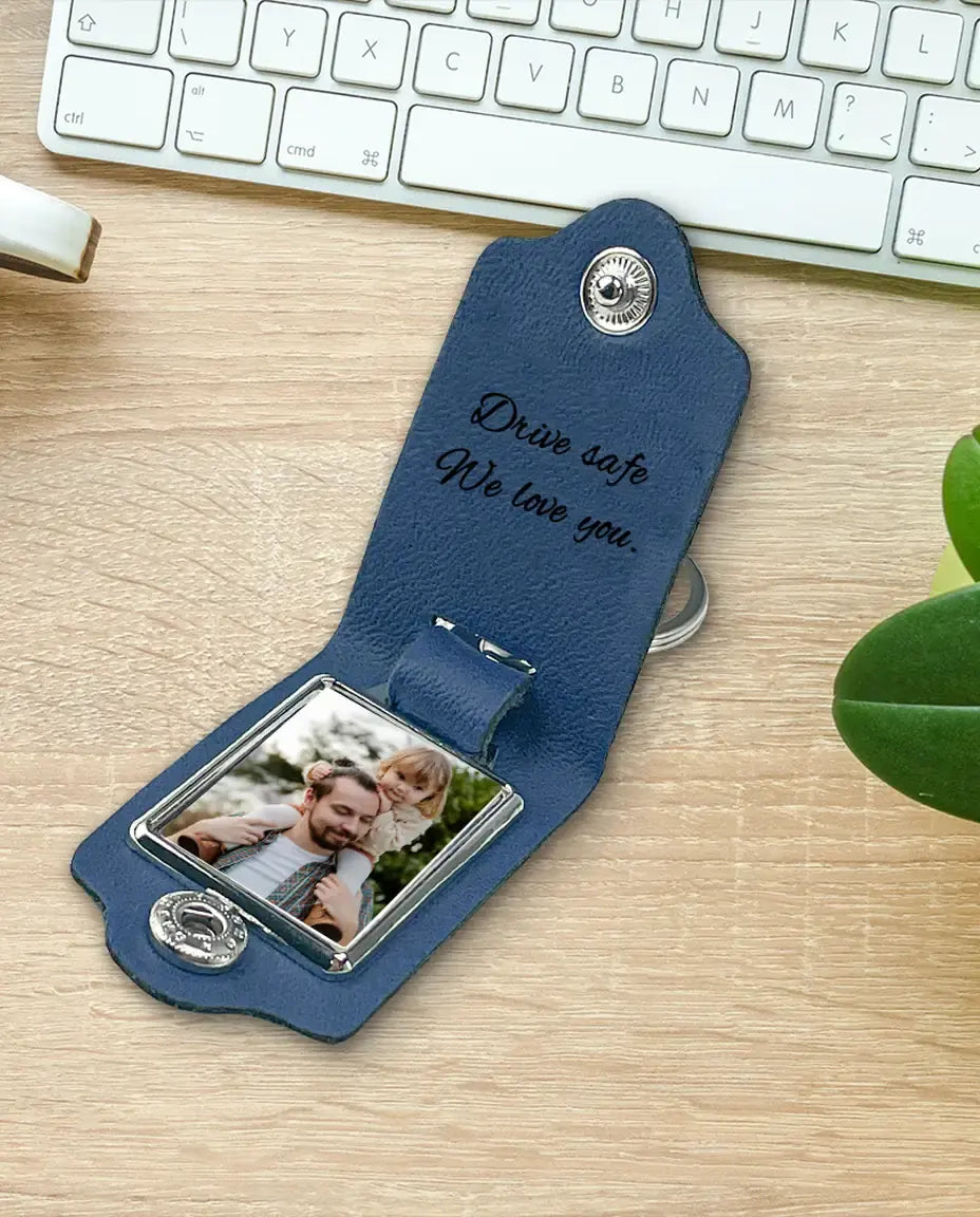 Blue faux leather monogram photo keychain on a desk with a plant