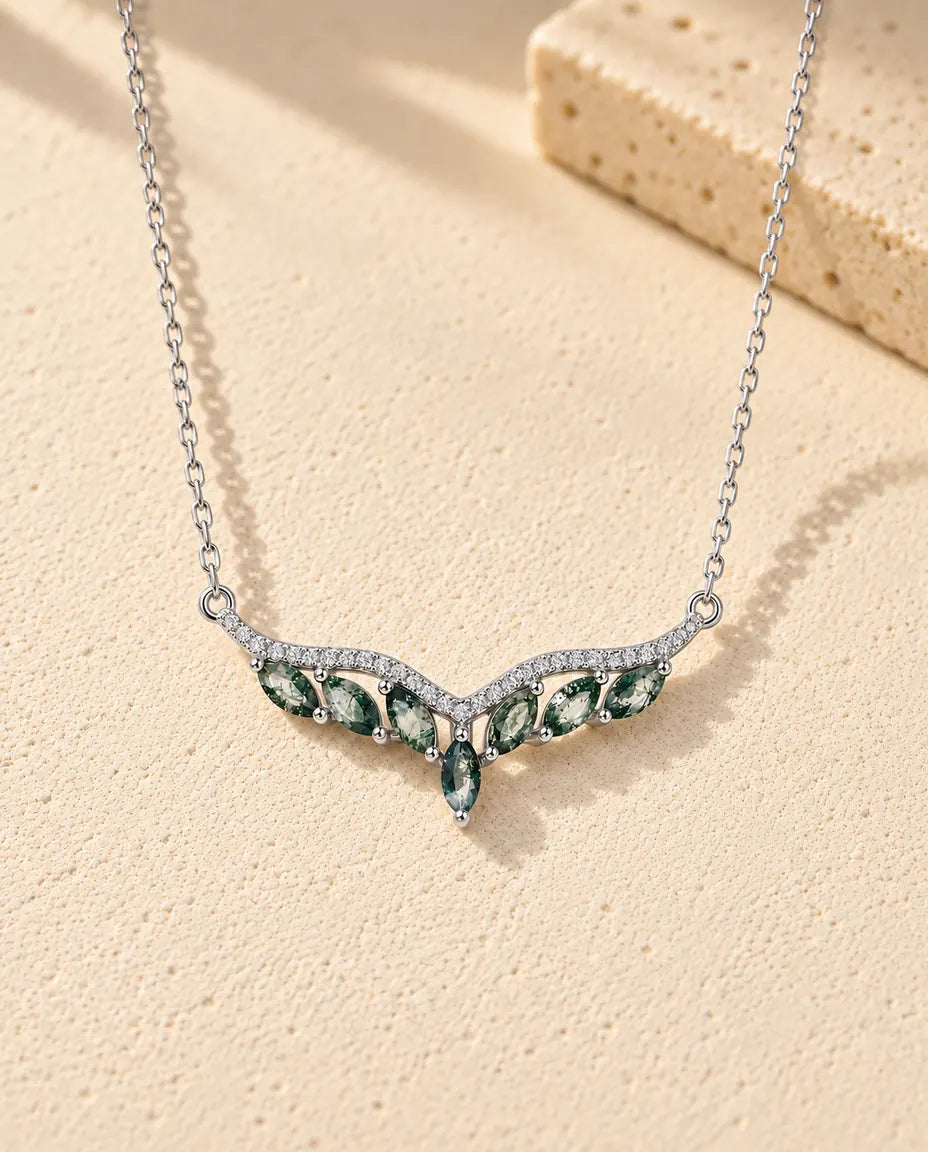 Moss Agate Chevron Necklace in 925 Sterling Silver - lying on a cream textured surface beside a travertine block