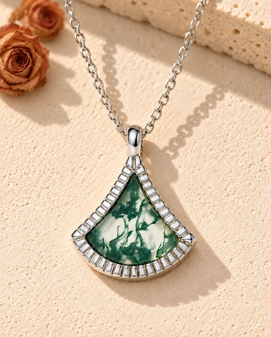 Moss Agate Fan Necklace in 925 Sterling Silver - lying on a cream textured surface beside a travertine block