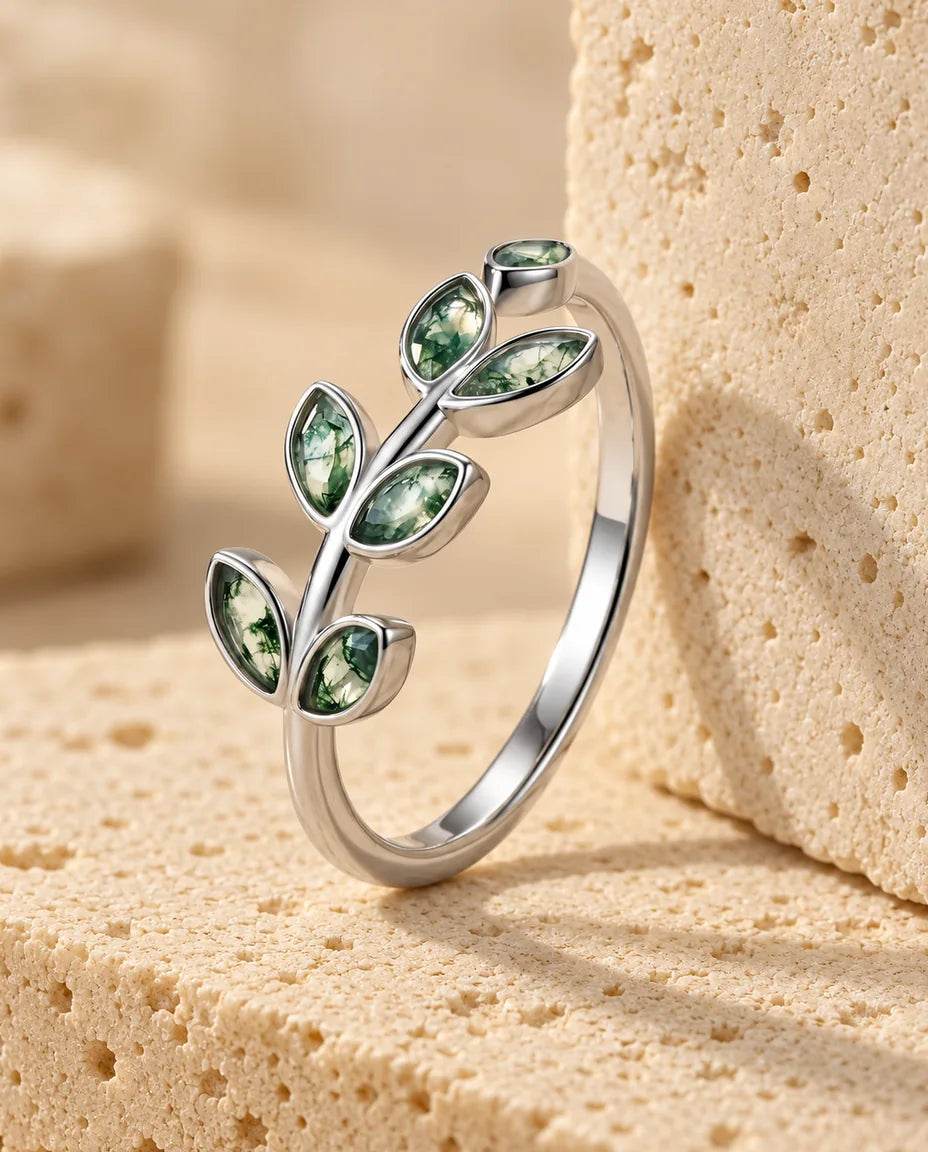 Olive Branch Moss Agate Ring - displayed on a travertine block