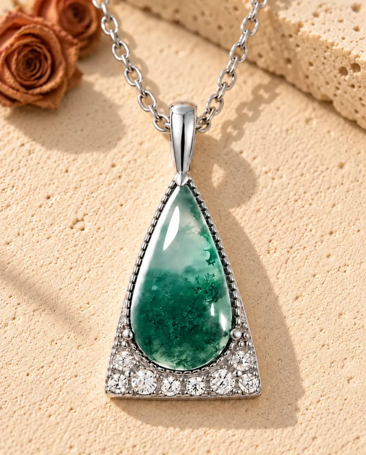 Moss Agate Triangle Necklace in 925 Sterling Silver - lying on a cream textured surface beside a travertine block