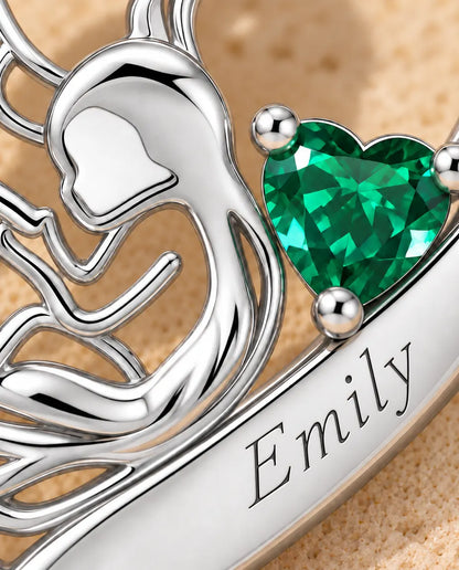 Macro detail of the cut-out mother and child figure, green birthstone and engraved name