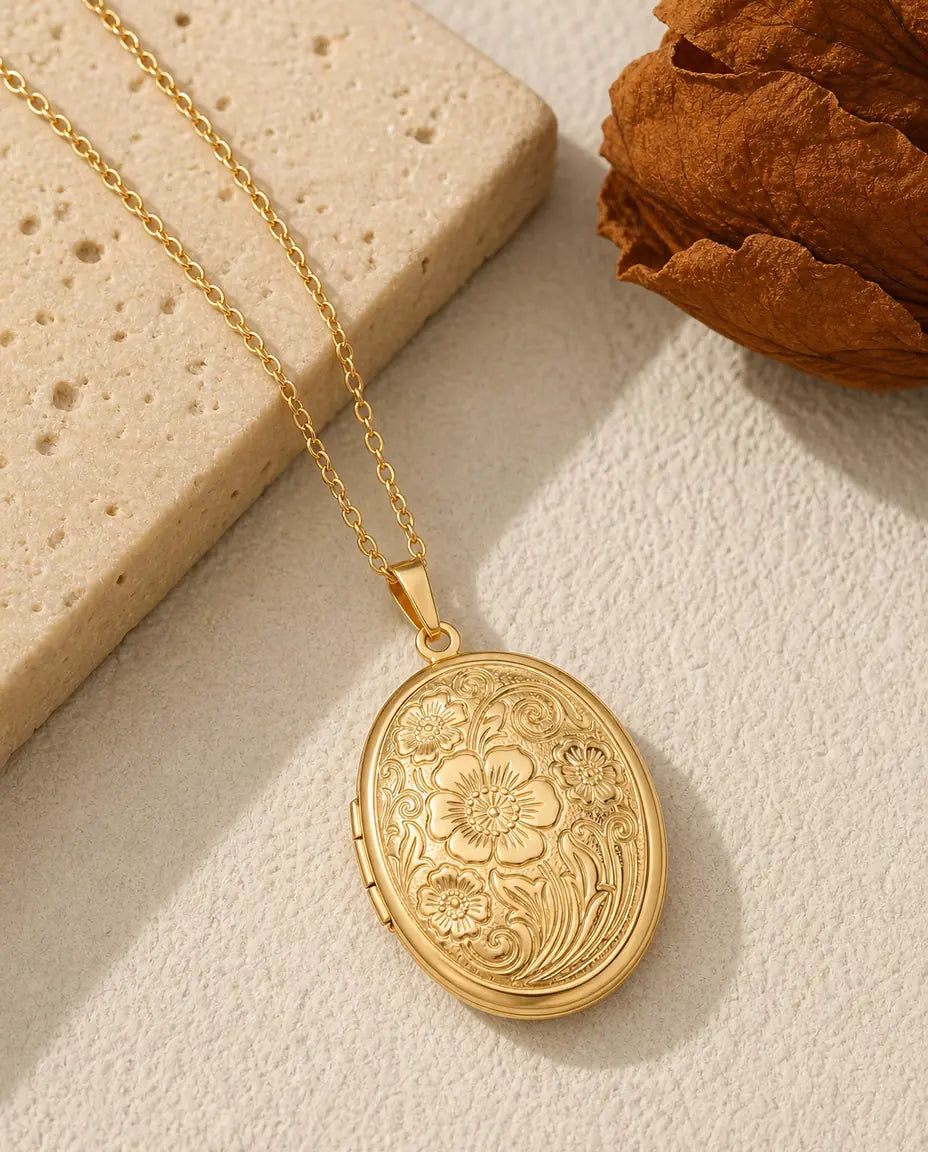 Gold oval photo locket necklace with engraved wildflower relief front