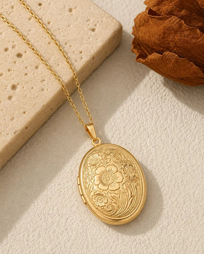 Gold oval photo locket necklace with engraved wildflower relief front