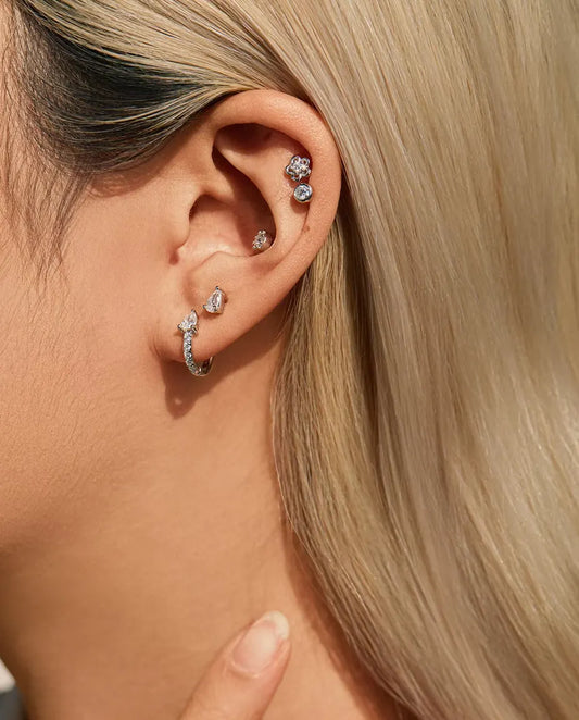 Pear Moissanite Stud Earrings in 925 Sterling Silver - worn on a model with her hand at her neck