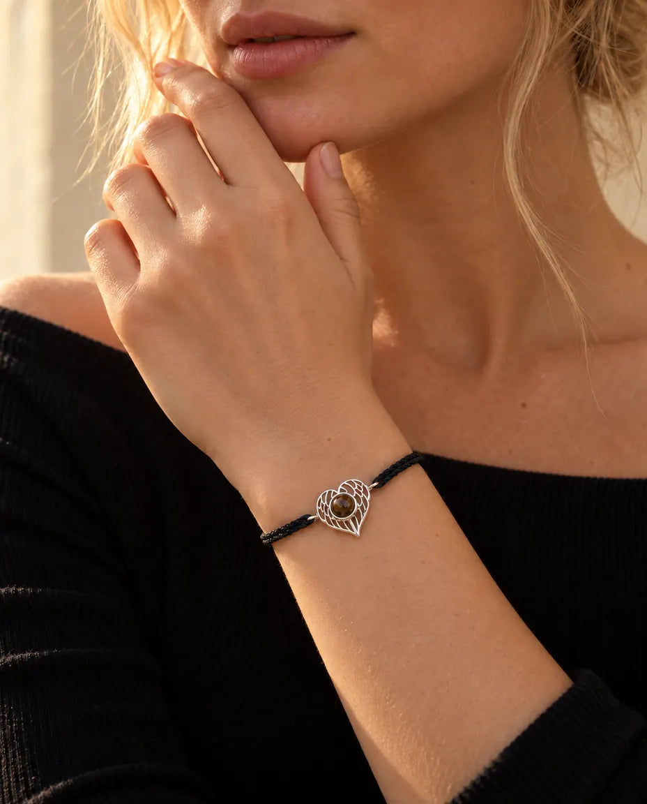 Woman with her fingertips at her jaw wearing the silver tone angel wing heart rope bracelet