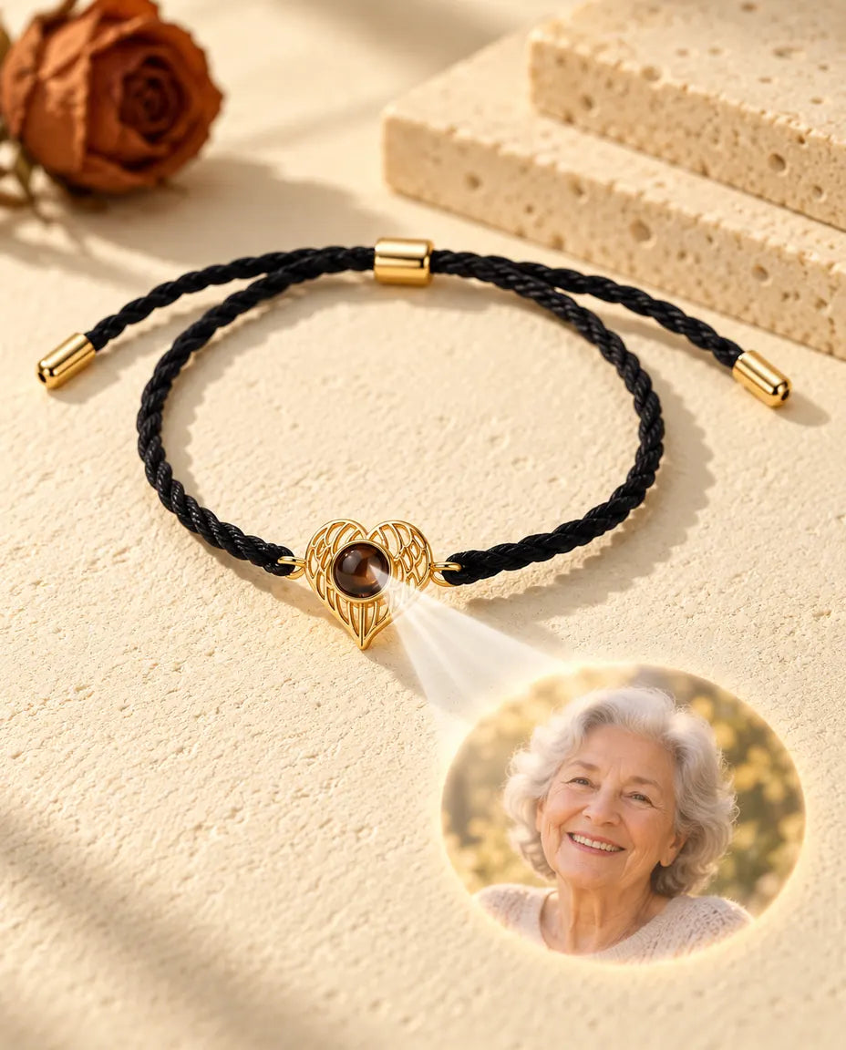 Light through the brown stone of the gold tone wing heart projects a round photo of a smiling grandmother