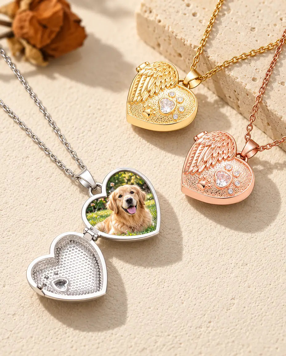 Silver tone angel wing paw print heart photo locket opened to show a golden retriever photo inside, beside closed gold tone and rose gold tone lockets