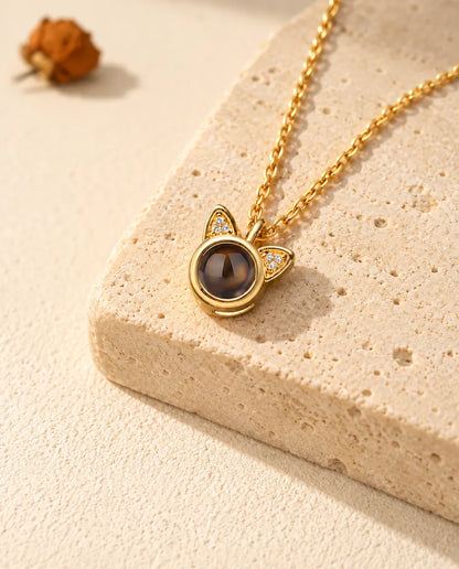 Personalized gold tone cat ear photo projection necklace on a travertine block