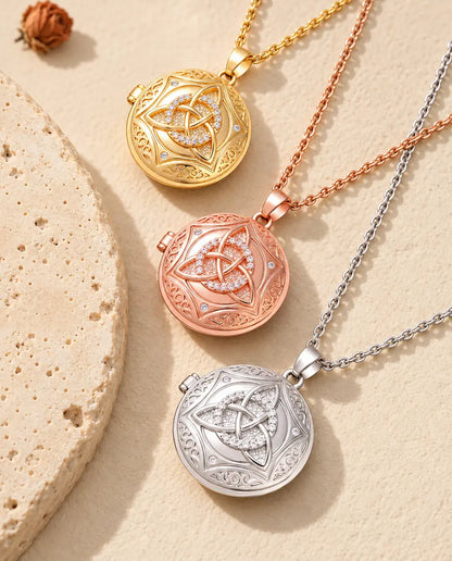 Gold tone, rose gold tone and silver Celtic knot lockets stacked beside a travertine slab