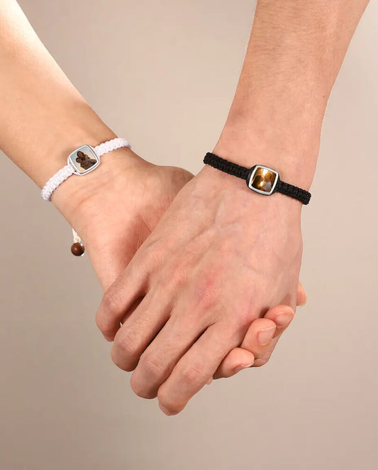 Couple holding hands wearing matching black and white photo charm bracelets