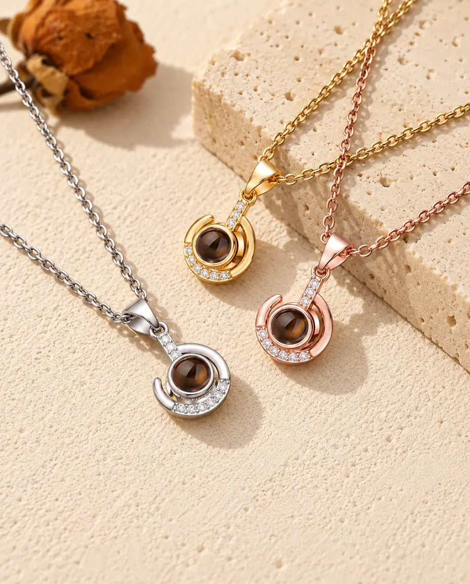 Silver tone, gold tone and rose gold tone crescent swirl pendants on travertine