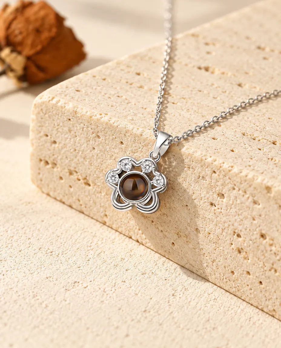 Personalized silver tone dainty paw print photo projection necklace on a travertine block
