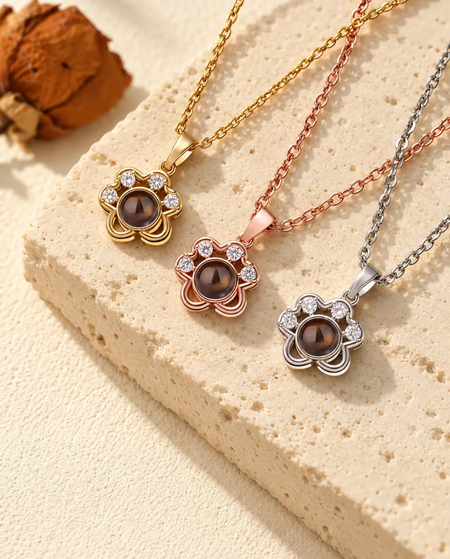 Gold tone, rose gold tone and silver tone paw print necklaces laid diagonally on travertine