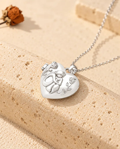 Personalized dog lover heart photo locket necklace in silver tone with a woman hugging her dog and roses, on travertine