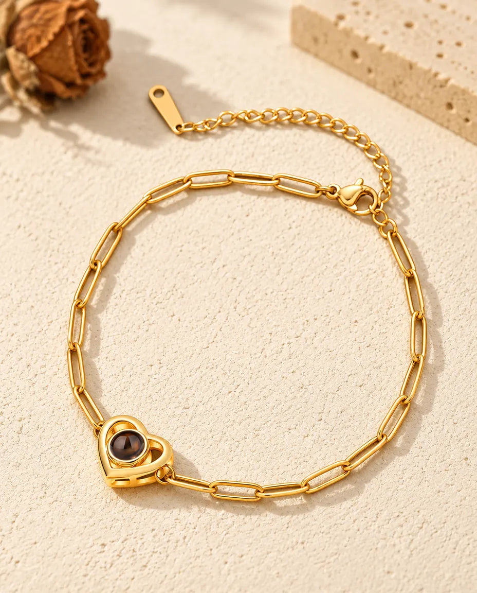 Gold tone double heart photo projection bracelet resting on cream plaster