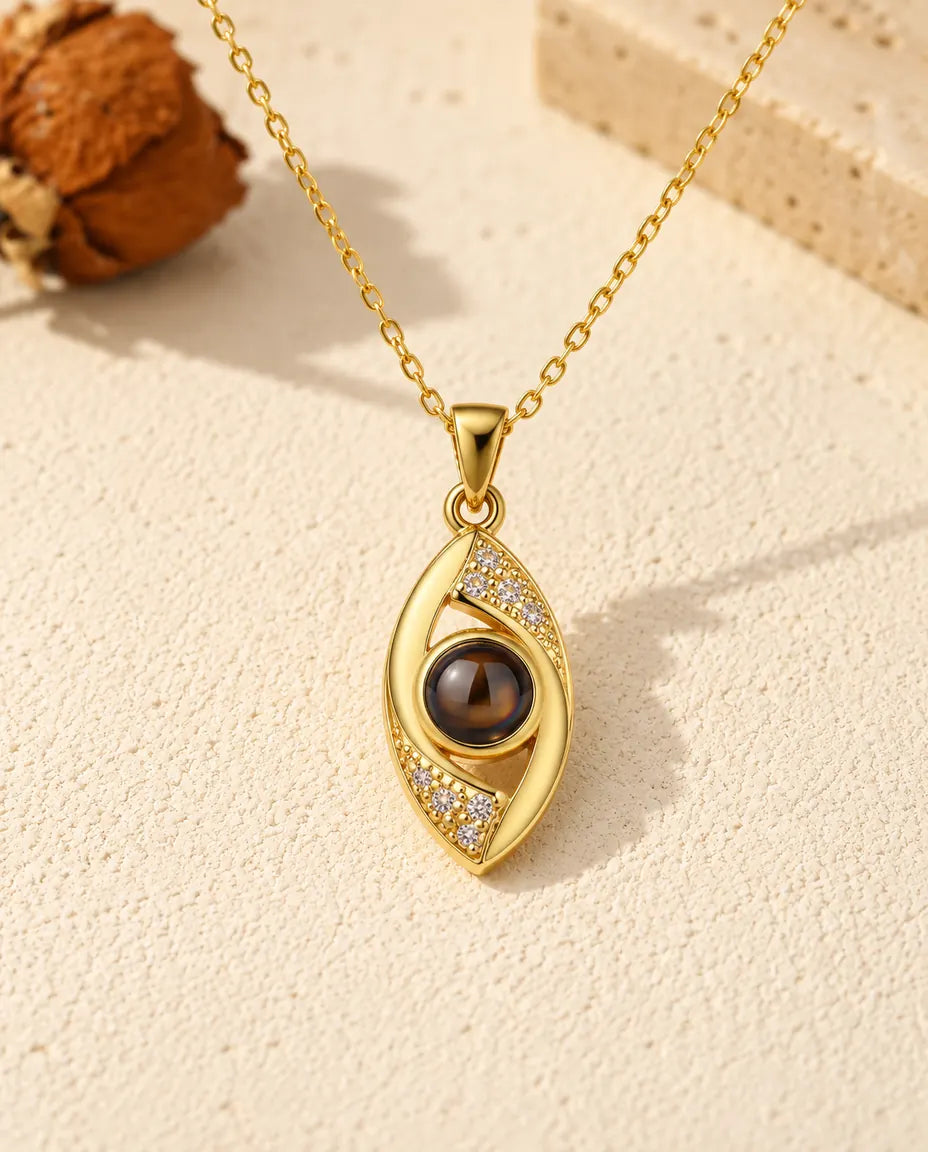 Front view of the gold tone almond eye pendant with the projection stone as its iris