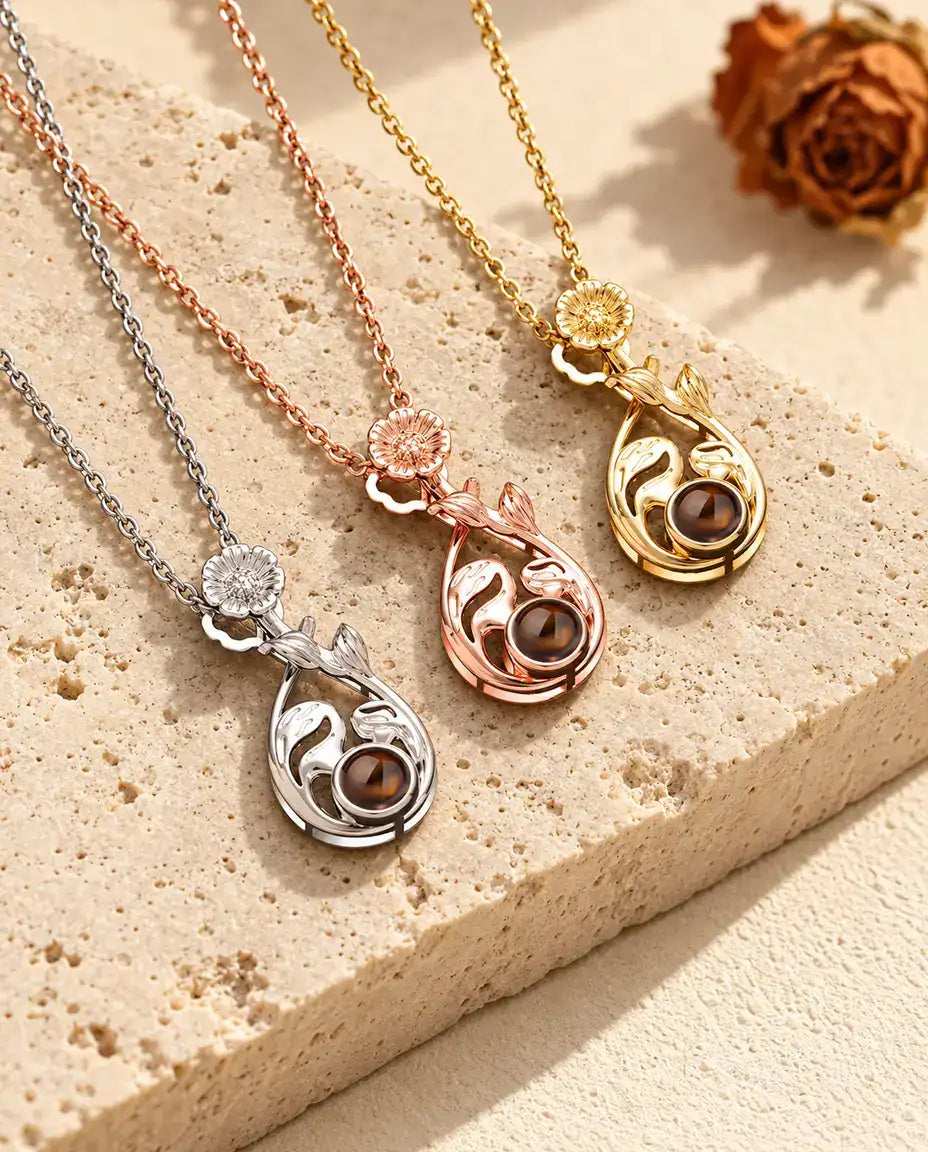 Three flower teardrop necklaces side by side with leaf swirls