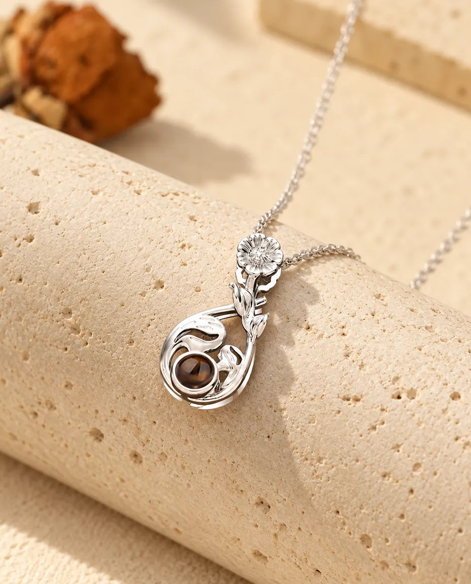Silver tone flower teardrop projection necklace hanging over travertine