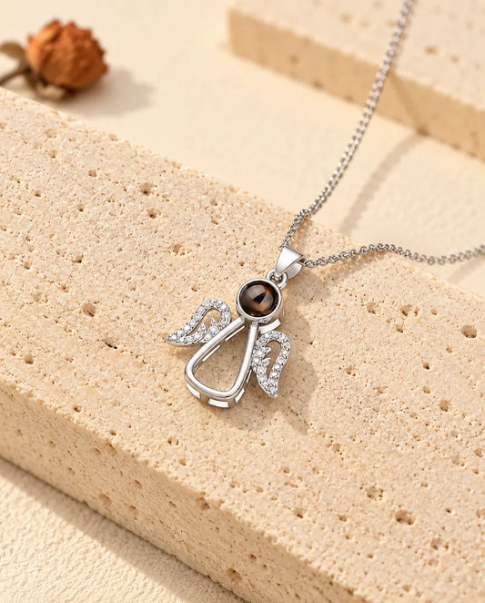 Personalized silver tone guardian angel photo projection necklace on a travertine slab
